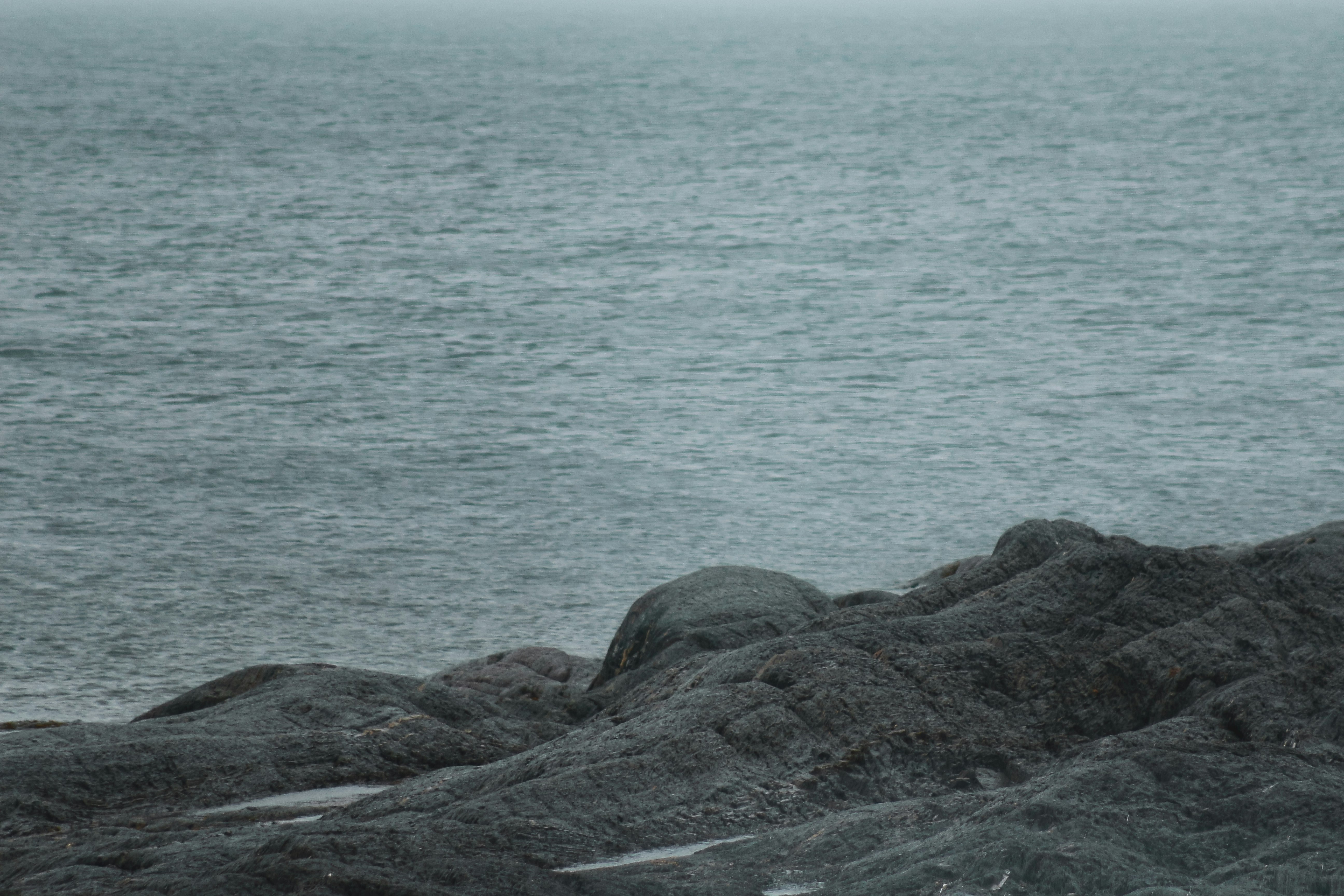 black rock formation near body of water during daytime